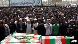 An Iranian cleric prays over the coffins of the victims of the Zahedan attacks during a mass funeral in the southeastern Iranian city on July 17.