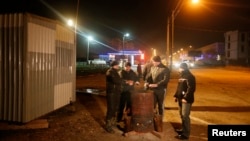 Crimean Tatars with a "self-preservation" patrol warm themselves around a fire on a night shift on the outskirts of Simferopol. 