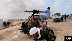 Libyan rebel fighters try to defend a gate of the north-central key Libyan oil town of Ras Lanuf as Muammar Qaddafi's loyalist forces approach their positions on March 10.