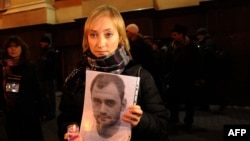 Darya Korsak, the wife of the imprisoned Alyaksandr Atroshchankau, holds her husband's portrait during a protest in front of the headquarters of the Belarusian KGB in Minsk less than a month after the disputed presidential election of December 2010.