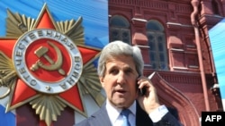 U.S. Secretary of State John Kerry talks on a cell phone as he walks on May 7 in front of a giant poster marking the upcoming Victory Day on the Red Square in Moscow.