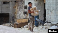 A boy carries bread as he walks in Latamneh city, which was hit by Russian air strikes, in the northern countryside of Hama.