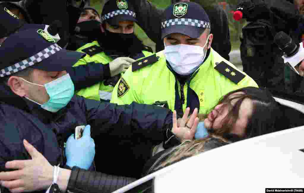 Police officers in the Georgian capital, Tbilisi, detain supporters of the opposition Pine Cone (Girchi) party on April 23 as they protest against the extension of the state of emergency in the country.