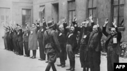 A member of the Nazi SS inspects a group of Jewish workers in the Warsaw ghetto in April 1943.