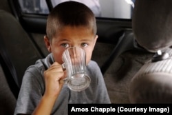 A Turkmen boy swills water on a baking afternoon in July.