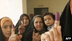 Iraqi women show their ink-stained fingers after casting their votes at a polling station in Baqubah.