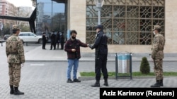 An Azeri law enforcement officer checks a resident's permission to leave home received in a text message, after the authorities imposed restrictions on movement to prevent the spread of the coronavirus disease in Baku.