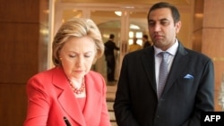 U.S. Secretary of State Hillary Rodham Clinton signs the memorial book for the terrorist attacks at the Taj Mahal Palace Hotel as General Manager Karambir Kang looks on.