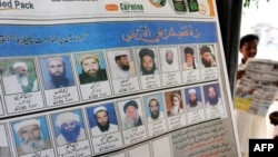 A newspaper featuring mugshots of radical cleric Maulana Fazlluah and other militants hangs on a tree at a roadside stall in Islamabad.