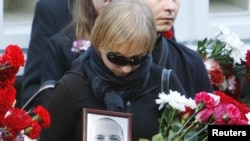 A mourner carries a portrait of Belarusian journalist Aleh Byabenin at his funeral in Minsk on September 6.