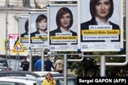 A woman walks past campaign posters for presidential candidate Maia Sandu in Chisinau on October 28.