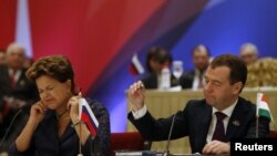 Brazilian and Russian Presidents Dilma Rousseff (left) and Dmitry Medvedev adjust their microphones while addressing the media at the end of the plenary session of the BRICS Summit in New Delhi on March 29.