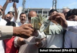 People burn U.S. dollars in protest of the deteriorating economy in Islamabad in May 2019.