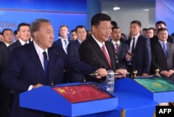 Chinese President Xi Jinping (right) and his Kazakh counterpart Nursultan Nazarbaev (left) turn on a symbolic lever during a ceremony in Astana on June 8, 2017, for a new container service.