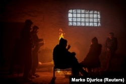 Migrants warm themselves by a fire inside a derelict customs warehouse in Belgrade. (file photo)