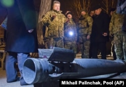 Dressed in military fatigues, Ukrainian President Petro Poroshenko talks to reporters beside an unexploded rocket in Kramatorsk in February 2015.