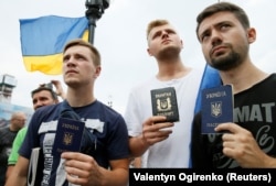 People holding their Ukrainian passports at a rally in central Kyiv to support Mikheil Saakashvili, who was stripped of his Ukrainian citizenship.