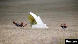 Malaysian air-crash investigators take photos of the crash site of Flight MH17 on July 22.