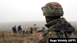 A Ukrainian serviceman looks as volunteers dig trenches on the coast of the Sea of Azov near the Ukrainian city of Mariupol on November 26.