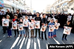 Iranian boys hold images of one of the victims, 4-year-old Mohammad Taha Eghdami, during a public funeral ceremony for those killed in the attack in the southwestern Iranian city of Ahvaz on September 24.