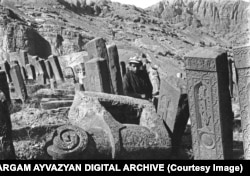 A young man poses among khachkars and a stone ram in the Julfa cemetery in 1915.