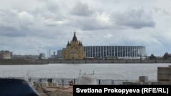 An Orthodox church stands in front of the Nizhny Novgorod football stadium.