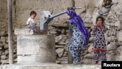 A young girl pumps water from a well in the village of Manugay in the Pech River Valley of Kunar Province, Afghanistan, in June.