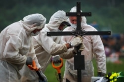 Gravediggers wearing personal protective equipment bury a person who is believed to have died of COVID-19 in St. Petersburg earlier this year.