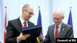 Ukrainian Prime Minister Arseniy Yatsenyuk (left) and European Council President Herman Van Rompuy exchange documents at the signing ceremony in Brussels on March 21.