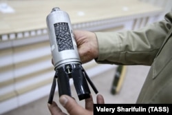 An Azerbaijani official with a cluster bomb (cut open for display purposes) used in Smerch rockets. Seventy-two such bomblets can be carried inside a single rocket.