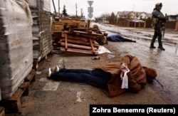 A body with its hands bound by white cloth lies on a street in Bucha on April 3.