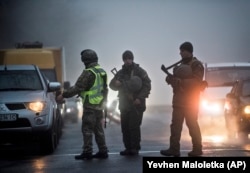 Ukrainian security officers search a car at a checkpoint near the city of Mariupol on the south coast of the Sea of Azov in eastern Ukraine.