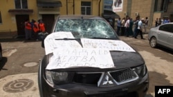 A damaged car covered by posters reading "Dadayev is a victim of outrage!" outside the office of the Committee Against Torture in Grozny after it was ransacked on June 3, 2015.