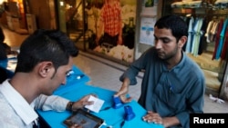 A customer (right) has his thumb scanned for biometric verification before purchasing a SIM card, a procedure intended to prevent people from making illegal copies. (file photo)