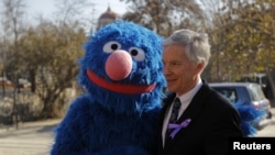 U.S. Ambassador to Afghanistan Ryan Crocker poses for pictures with "Sesame Street" character Grover before the inauguration of a show in Kabul on November 30.