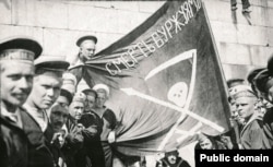 Sailors of Kronstadt during the revolutionary unrest of 1917 pose with a flag vowing "Death to the bourgeoisie."