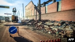 Workers repair a power line near the wall of a local zinc plant in Chelyabinsk that was damaged by a shockwave from a meteor.