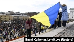 People hold a giant Ukrainian flag as they take part in an ecumenical prayer moment in support of Ukraine amid Russia's invasion in Helsinki on April 18.