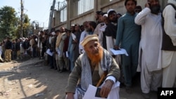 Afghan nationals carry their passports as they wait to extend their visas outside the Pakistani immigration office in Peshawar. (file photo)