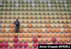 A worker cleans seats in the newly refurbished Sukhumi stadium, which has been revamped ahead of the soccer tournament.