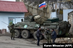 Men interact with a Russian peacekeeper in the town of Lachin on November 30, 2020.