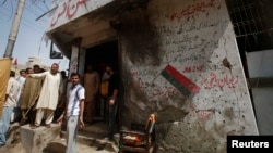 Men stand outside the campaign offices of the Muttahida Qaumi Movement (MQM) political party in Karachi on April 26, after a bomb blast.