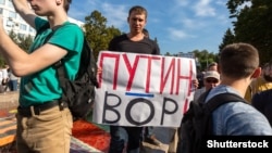 A protester holds a sign reading "Putin Is A Thief" during a rally against raising the retirement age, in Samara on September 9.