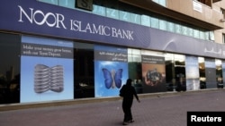 A woman walks past a branch of Noor Islamic Bank in Dubai.