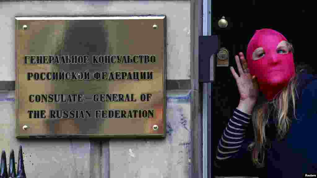 A protester gestures next to a sign outside the Russian Consulate building during a demonstration of support for Pussy Riot in Edinburgh, Scotland, on August 17.