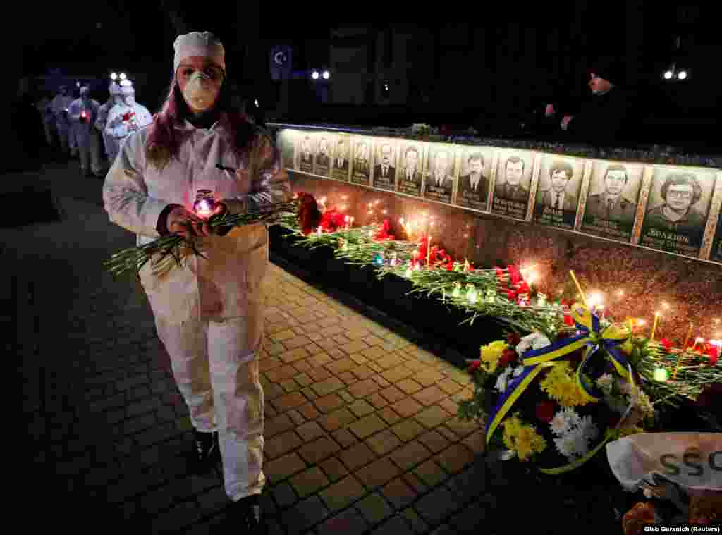 Staff from the Chernobyl nuclear plant hold candles as they visit a memorial dedicated to firefighters and workers who died after the disaster, during an overnight service in Slavutych.&nbsp;