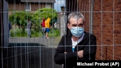 A Romanian worker stands behind a fence that was set up at the entrance of housing for Romania slaughterhouse workers in Rosendahl, Germany, on May 12.