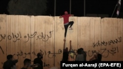 An Iraqi protester tries to climb the concrete wall of the Iranian Consulate in Karbala on November 3.