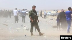 A member of Iraqi Kurdish security forces stands guard as families fleeing violence in the city of Mosul wait at a checkpoint in outskirts of Irbil on June 10.