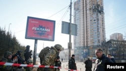 Ukrainian servicemen are seen near an apartment building damaged by shelling in Kyiv on February 26.